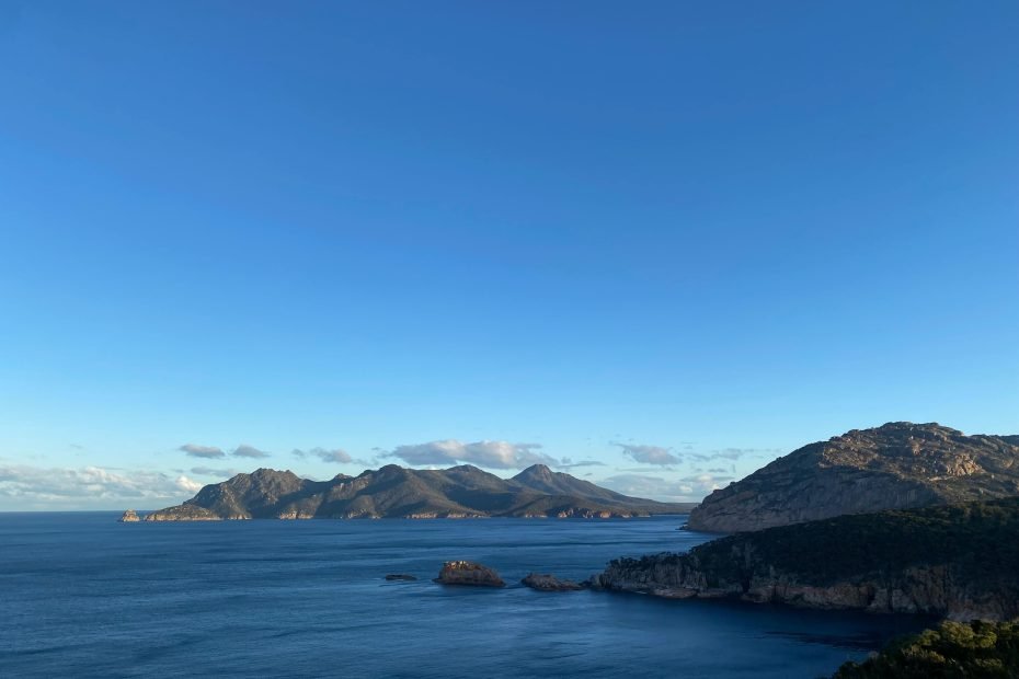 远眺塔斯马尼亚州沿海山脉的景色，海岸线与蓝天交相辉映，展现出自然的壮丽之美。